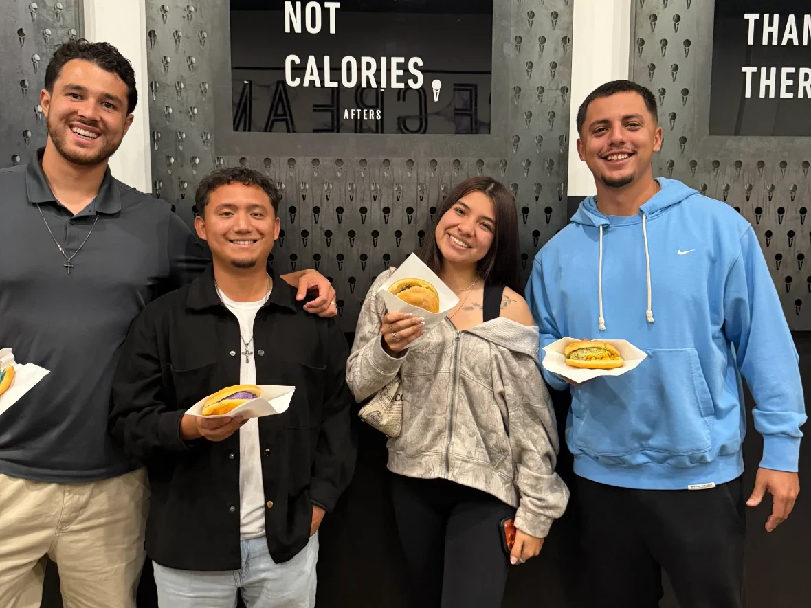 Four smiling friends holding stuffed ice cream sandwiches.