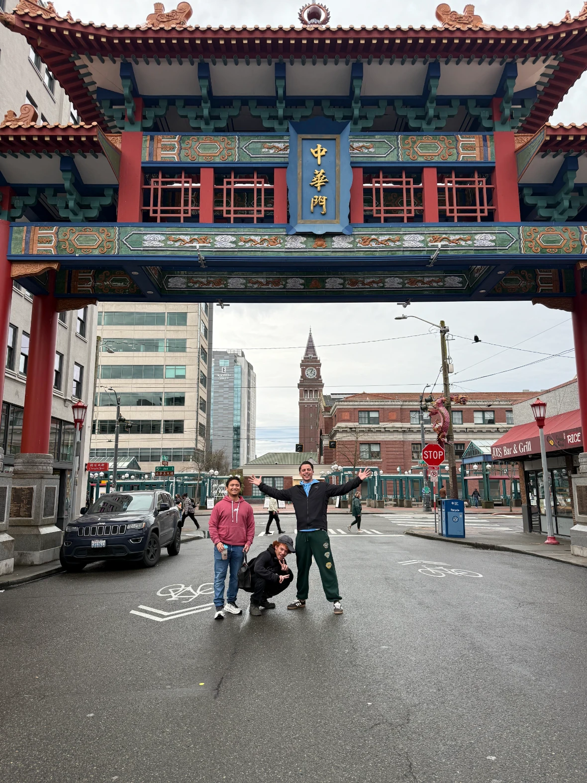 Three people posing under the ornate red.